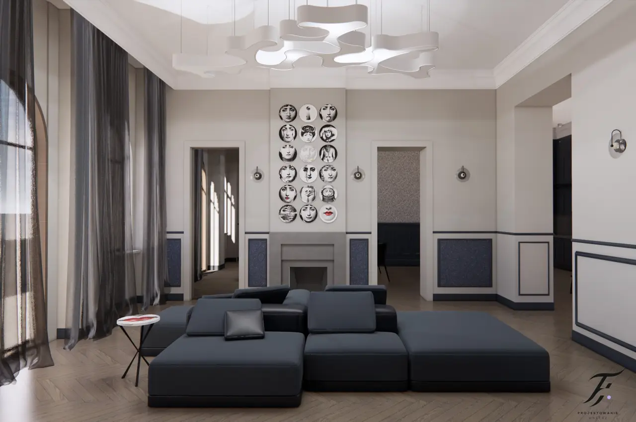 salon o eleganckim i minimalistycznym designie. W centralnej części pomieszczenia znajduje się duża,  sofa modułowa, ustawiona na podłodze z jasnego drewna ułożonego we wzór jodełki. Na ścianie za sofą wiszą okrągłe talerze ozdobione różnymi grafikami twarzy, tworząc ciekawy akcent dekoracyjny. Na suficie zawieszona jest nowoczesna lampa o nieregularnych, organicznych kształtach. Kolorystyka wnętrza jest stonowana, dominują odcienie szarości, beżu i niebieskiego, co nadaje przestrzeni spokojnego charakteru.